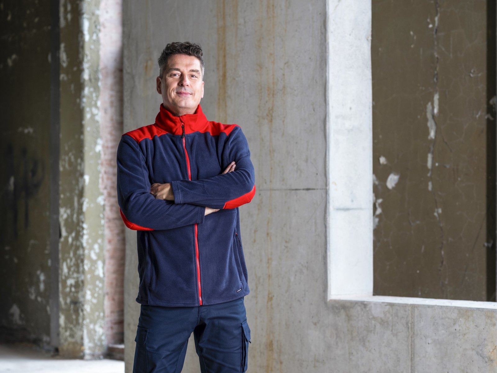 Vakman in een Santino-jas in navy en rood, klaar voor je logo